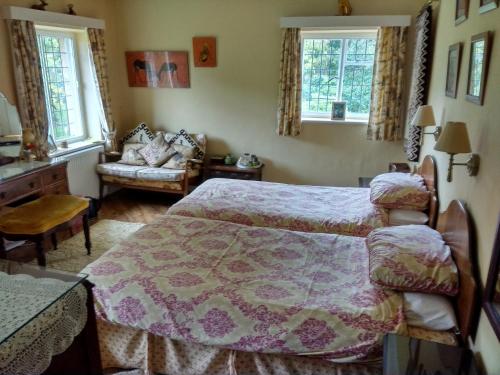 a bedroom with a bed and a couch and two windows at Thornley House in Hexham