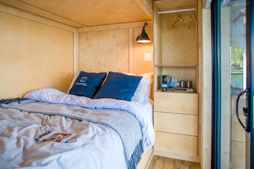 a bed with blue pillows in a tiny house at Flotel in Salaberry de Valleyfield