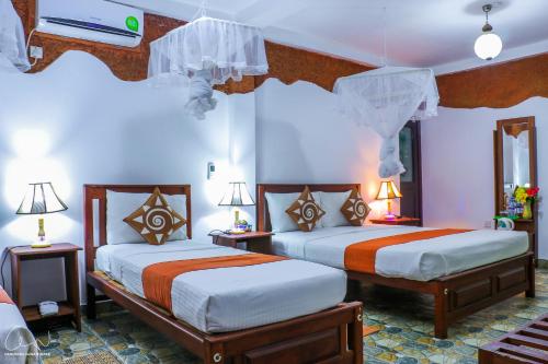a hotel room with two beds and two lamps at Sigiri Heritage Villa in Sigiriya