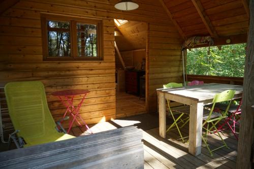 a porch of a cabin with a table and chairs at La Cabane aux Rêves in Sepx