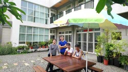 een man en drie kinderen aan een tafel met een paraplu bij Tian Ying Home Stay in Liugui