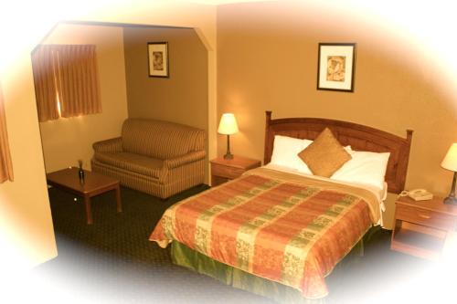 a hotel room with a bed and a chair at Holland Inn and Suites in Taft
