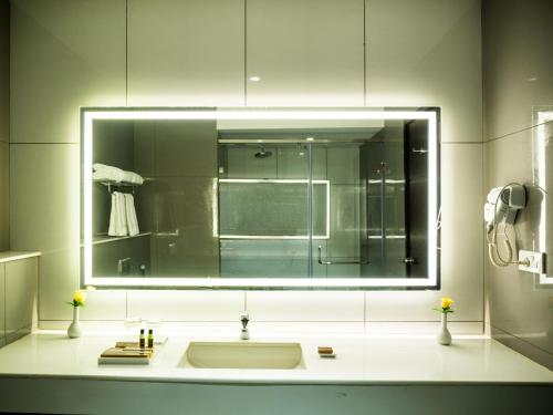a bathroom with a sink and a large mirror at Grand Ashok in Thanjāvūr