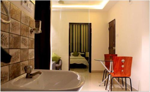 a bathroom with a tub and a table and a bedroom at Magnus Calypso Suites Viman Nagar in Pune