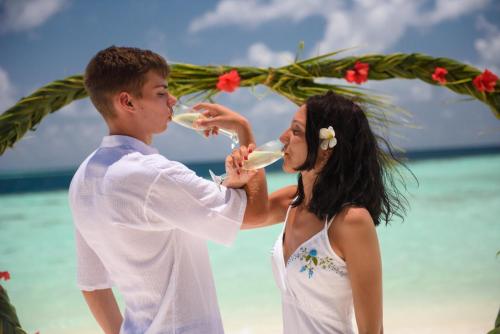 a man and a woman drinking wine on the beach at Biyadhoo Island Resort in Biyadhoo