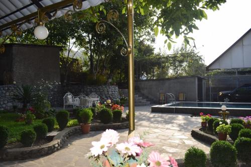 a garden with a fountain and flowers and a pole at Family Hotel Lago & Wine Cellar in Lagodekhi