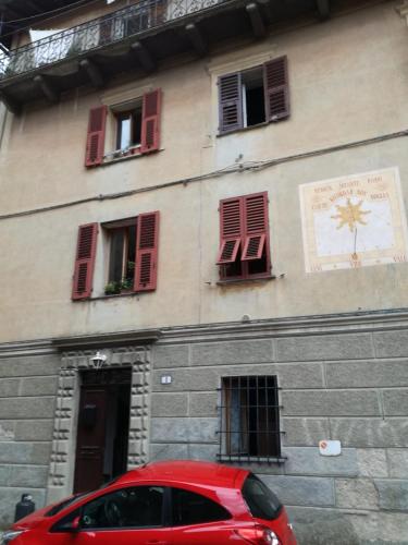 ein rotes Auto, das vor einem Gebäude mit Fenstern parkt in der Unterkunft Comodo appartamento nel centro di Sassello in Sassello