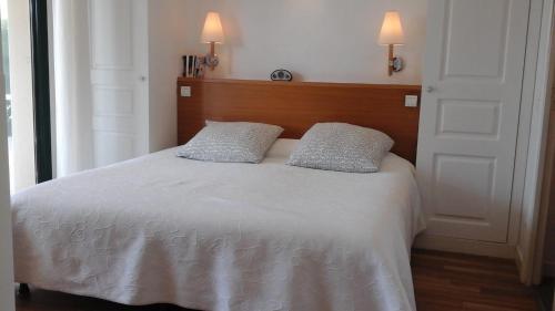 a bedroom with a white bed with two pillows at Saint Denac - Golf de la Baule in Saint-André-des-Eaux