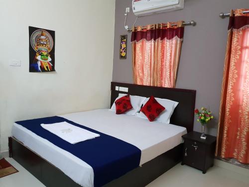 a bedroom with a bed with blue sheets and red pillows at SP Plaza Service Apartment in Trivandrum