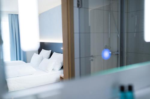 a bedroom with a bed with white pillows and a mirror at Hotel U7 in Metzingen