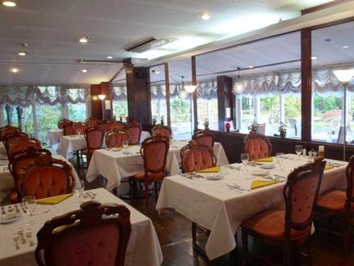a restaurant with tables and chairs with white tablecloths at Hotel Natural Garden Nikko in Nikko