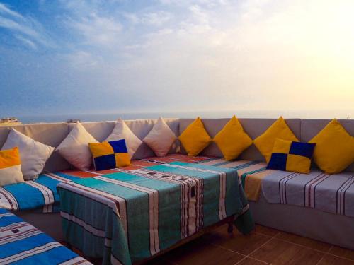 eine Couch mit bunten Kissen am Strand in der Unterkunft Original Surf Morocco in Tamraght Ouzdar