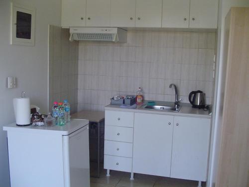 a small kitchen with white cabinets and a sink at Nina Rooms (apartments) in Artemida