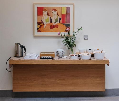 a table with bowls and dishes on it with a painting at La Alcoba del Agua Hotel Boutique in Sanlúcar de Barrameda