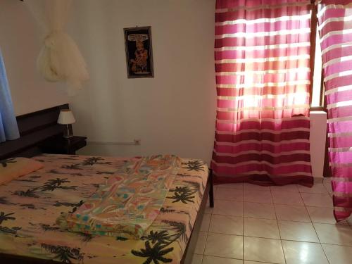 a bedroom with a bed and a pink curtain at Pensão Alcinda Bettencourt 100 meters to the Beachfront in Santa Maria
