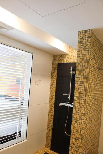 a bathroom with a shower with a tile wall at Aspira Skyy Sukhumvit 1 in Bangkok