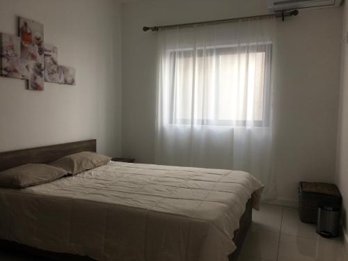 a bedroom with a bed and a window with white curtains at Ocean view in Flic-en-Flac