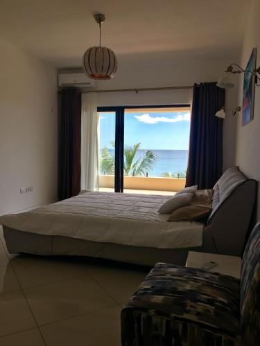 a bedroom with a large bed and a large window at Ocean view in Flic-en-Flac