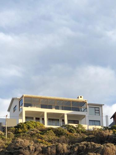 a white building on top of a cliff at Captain Sunshine Guest House in Jongensfontein