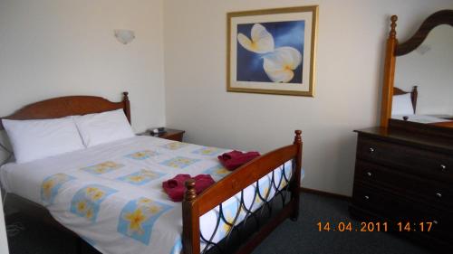 a bedroom with a bed and a painting on the wall at Summers Rest Units in Port Campbell