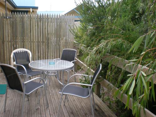a patio with a table and chairs on a wooden deck at Summers Rest Units in Port Campbell