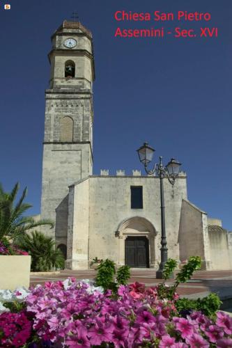 a clock tower with flowers in front of a building at Casa Giò in Assemini