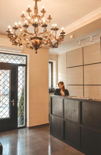 a woman sitting at a bar in a room with a chandelier at Eleon Boutique Hotel in Tbilisi City