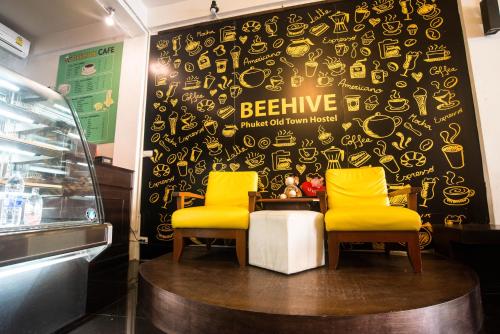two yellow chairs in front of a black wall with yellow signs at Beehive Phuket Old Town Hostel in Phuket Town