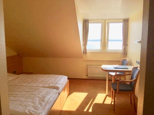 a bedroom with a bed and a desk and a window at Hotel Kieler Förde in Kiel
