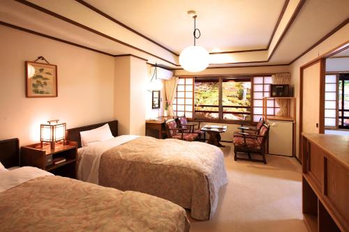 a hotel room with two beds and a table and chairs at Tsuruya Ryokan in Karuizawa