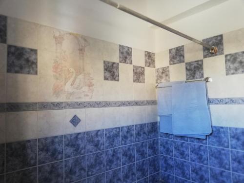 a blue tiled bathroom with a blue shower curtain at Chriselina Gottage in Paphos
