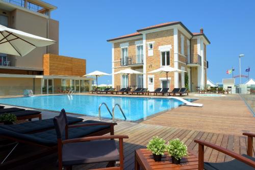 einen Pool mit Stühlen und Sonnenschirmen neben einem Gebäude in der Unterkunft Hotel Capanni in Bellaria-Igea Marina