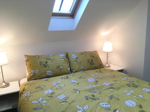 a bed with a green bedspread with blue flowers on it at Ty Glo Cottage in Brecon