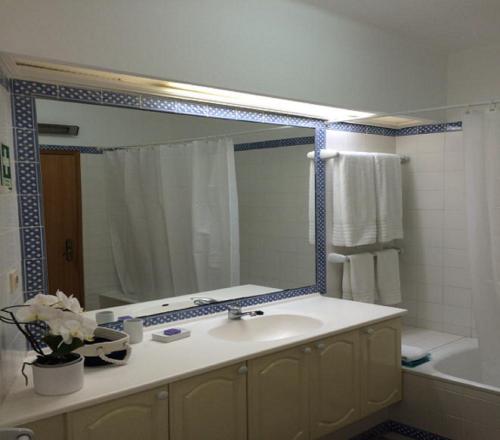 ein Badezimmer mit einem Waschbecken und einem großen Spiegel in der Unterkunft Ocean Terraces Vila Gaivota I in Ferragudo