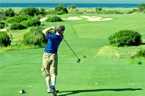 a man swinging a golf club on a golf course at Ocean Terraces Vila Gaivota I in Ferragudo