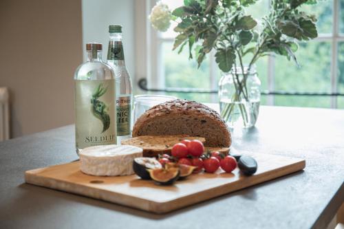 a loaf of bread on a cutting board next to a bottle of wine at The Cider Barn Boutique Holiday Cottage in Zeal Monachorum