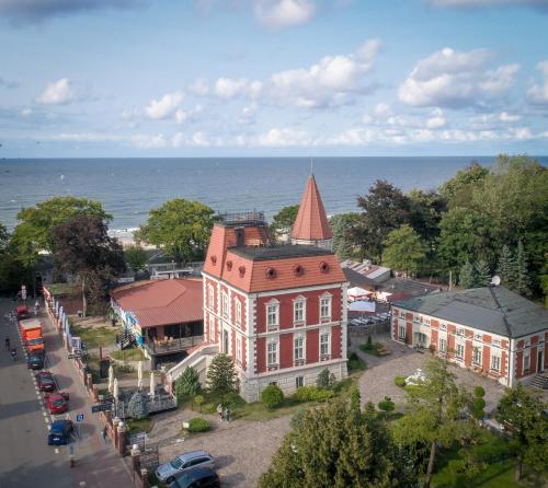 an old building with a red roof next to the water at VILLA RED by COLUMBUS Ustka in Ustka