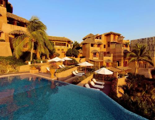 a swimming pool with chairs and umbrellas next to a building at La Casa Que Canta in Zihuatanejo