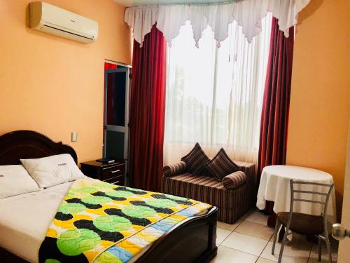 1 dormitorio con 1 cama, 1 silla y 1 ventana en D'ORLAND HOTEL, en Santo Domingo de los Colorados