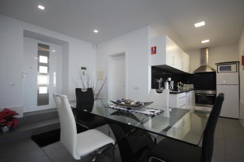 a kitchen with a glass table and white chairs at Villa Por do Sol in Estreito da Calheta