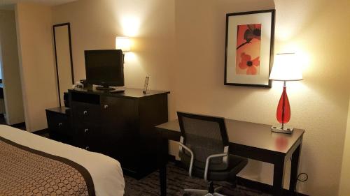 a hotel room with a bed and a desk and a television at Baymont by Wyndham Belleville Airport Area Free Airport Shuttle in Belleville