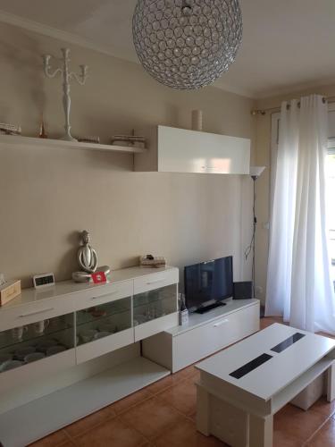 a white living room with a tv and a table at Apt a Calafell plage in Calafell