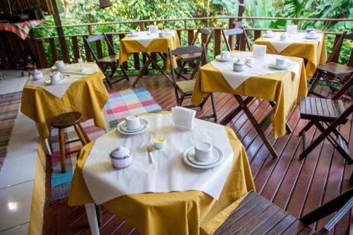 een rij tafels met gele tafelkleden op een terras bij Pousada Mãe Natureza Ilha Grande in Abraão