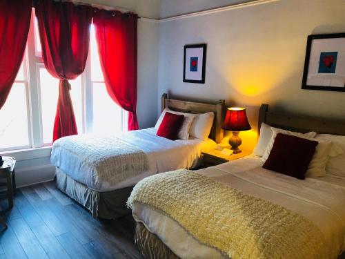 a bedroom with two beds and a window with red curtains at Hotel San Ramon in Bisbee
