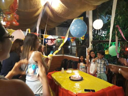 a group of people standing around a table with a birthday cake at Villa el despertar azul in Same
