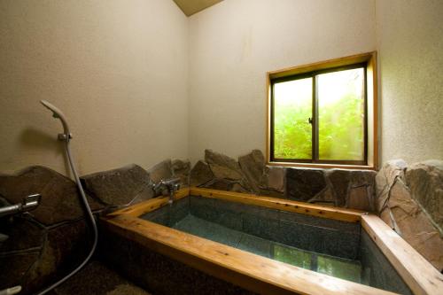 a bathroom with a large tub with a window at Oyado Uraku in Yufu