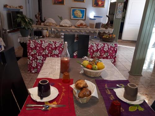 un tavolo con un piatto di cibo e un cesto di frutta di Les GREVILLEAS a La Plaine des Cafres