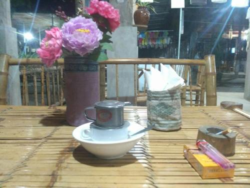 a coffee cup on a bowl on a table with flowers at Cò's House in Mai Chau