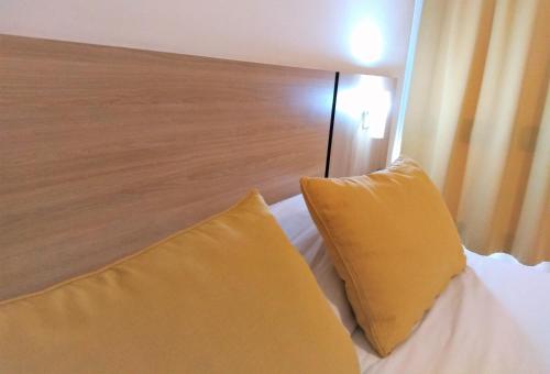 a bed with two yellow pillows on top of it at Premium Mendoza Apart Hotel in Mendoza