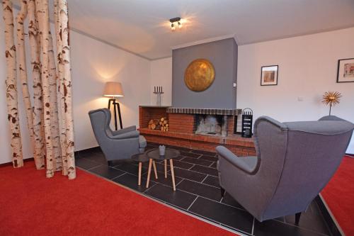 a living room with two chairs and a fireplace at Kingfisher-Ferienhaus in Westerdeichstrich